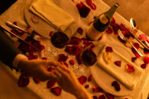 99+ Smooth Rizz Lines That Actually Work in 2025 6 A couple having romantic dinner table full of rose petals.